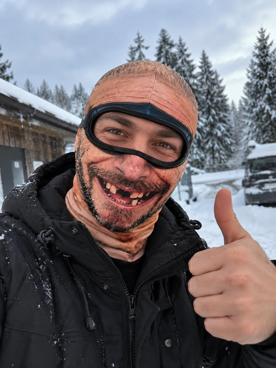 Person wearing the bald Old Man Mask giving a thumbs-up in the snow